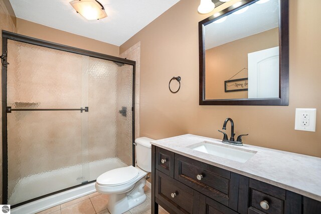 bathroom with walk in shower, vanity, toilet, and tile patterned flooring