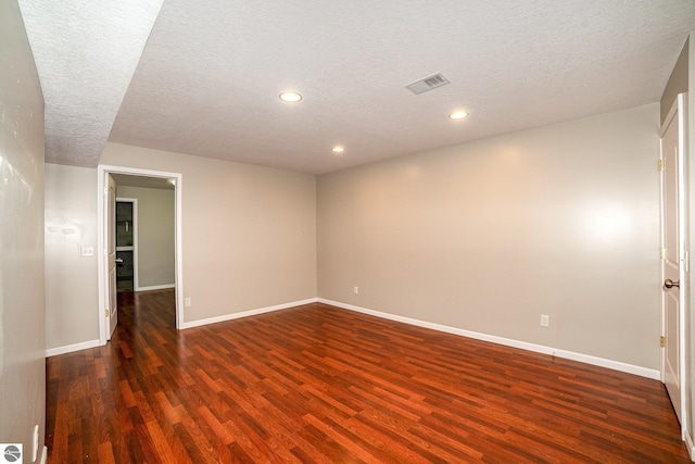 spare room featuring dark wood-type flooring and a textured ceiling