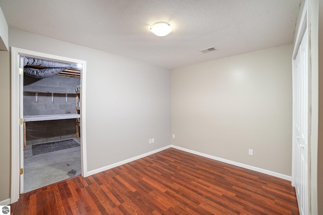 unfurnished bedroom featuring dark hardwood / wood-style flooring and a textured ceiling