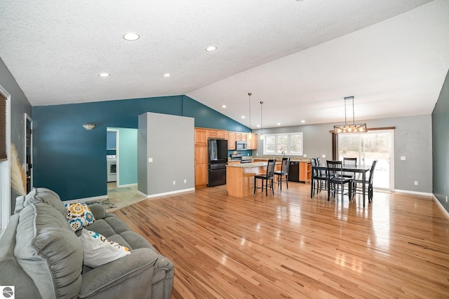 living room with vaulted ceiling, light hardwood / wood-style floors, and a textured ceiling