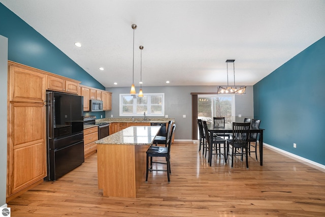 kitchen with sink, light stone counters, a center island, light wood-type flooring, and black appliances