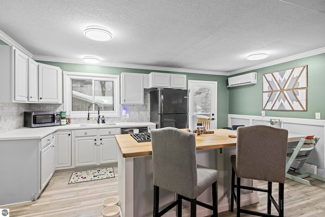 kitchen with white cabinetry, sink, black fridge, and butcher block countertops