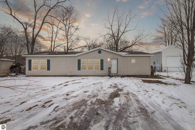 snow covered back of property featuring a garage