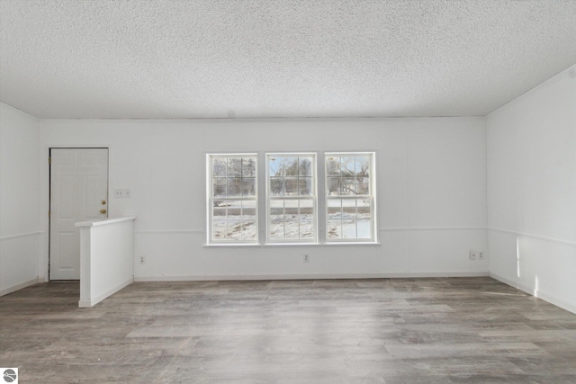 empty room with ornamental molding, a textured ceiling, and light hardwood / wood-style floors