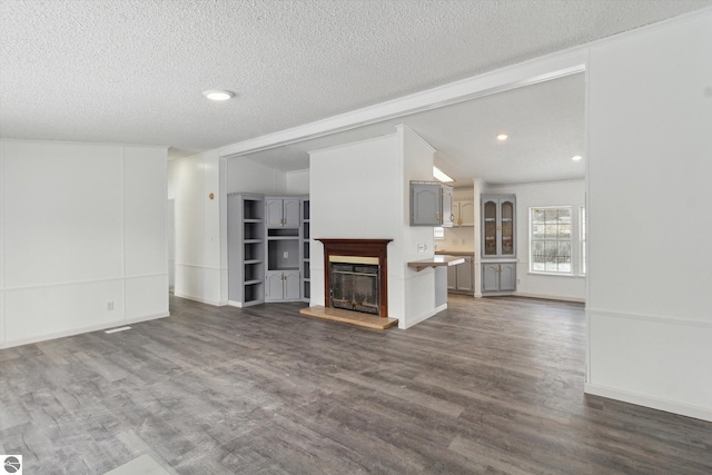 unfurnished living room featuring crown molding, dark hardwood / wood-style floors, and a textured ceiling