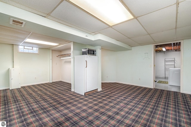 basement featuring washer / clothes dryer, a paneled ceiling, and white refrigerator