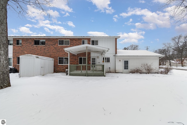 snow covered rear of property with a storage shed and a pergola