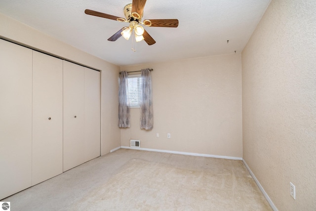 unfurnished bedroom with light carpet, ceiling fan, and a closet