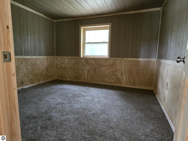 carpeted empty room with wooden ceiling and wood walls