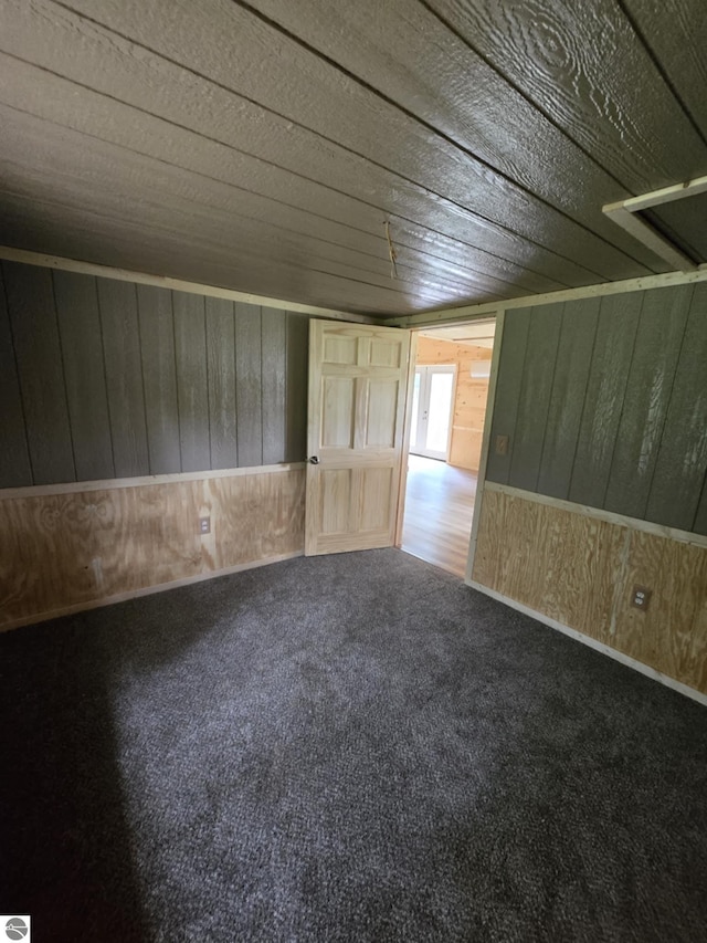 spare room featuring carpet flooring, wood ceiling, and wooden walls