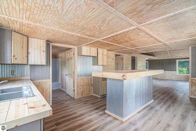 kitchen with light brown cabinetry, sink, a breakfast bar area, wood walls, and wooden ceiling