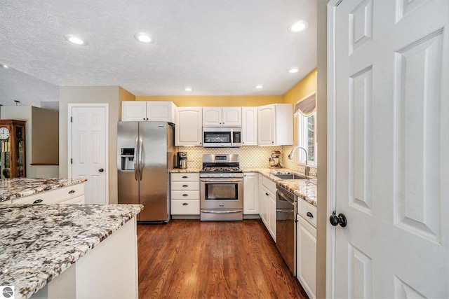 kitchen featuring a sink, stainless steel appliances, white cabinets, and dark wood-style flooring