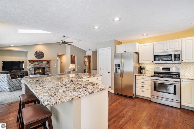 kitchen featuring lofted ceiling, dark wood-type flooring, appliances with stainless steel finishes, and a center island