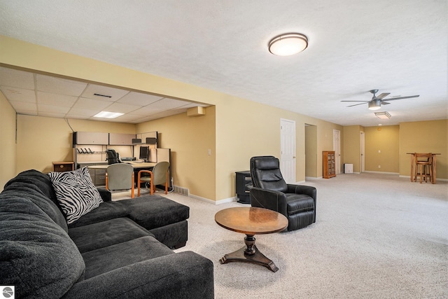 living area featuring visible vents, baseboards, a drop ceiling, ceiling fan, and light carpet