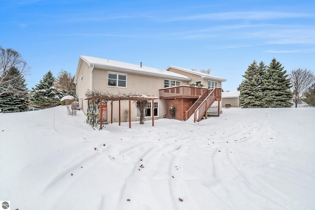 snow covered house with stairway and a wooden deck