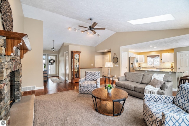 living room with visible vents, lofted ceiling with skylight, a healthy amount of sunlight, and a fireplace