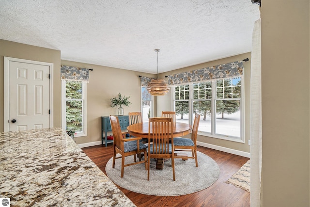 dining space featuring a textured ceiling, baseboards, and dark wood-style flooring