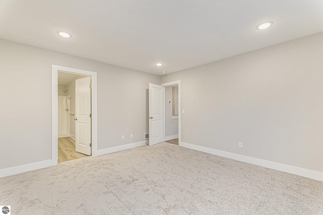 unfurnished bedroom featuring light carpet and connected bathroom