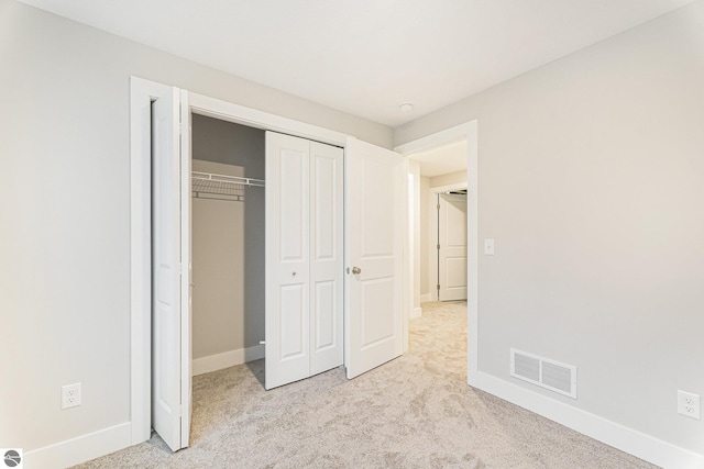 unfurnished bedroom featuring light colored carpet and a closet