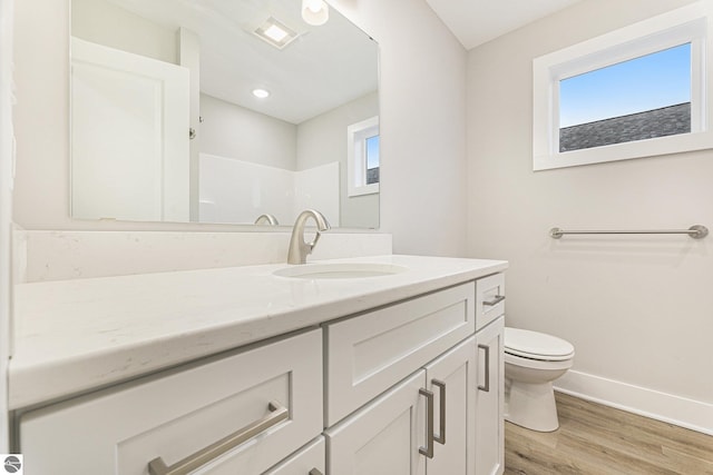 bathroom with hardwood / wood-style flooring, vanity, walk in shower, toilet, and a healthy amount of sunlight