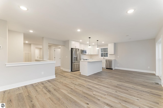 kitchen featuring pendant lighting, appliances with stainless steel finishes, a center island, white cabinets, and light wood-type flooring