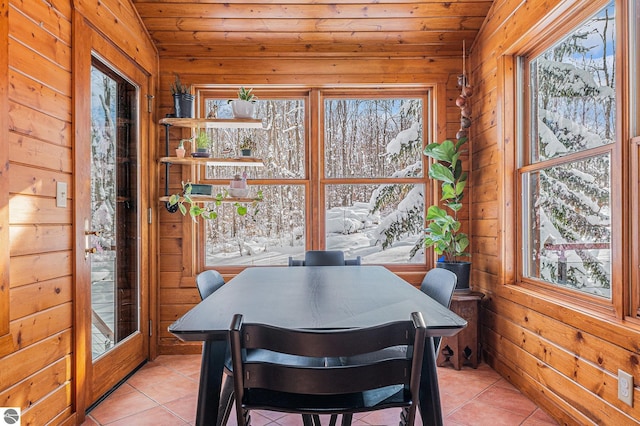 tiled dining area featuring wood walls, lofted ceiling, a wealth of natural light, and wooden ceiling