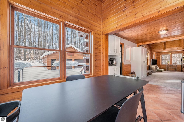 carpeted dining area featuring lofted ceiling, wood ceiling, and wood walls