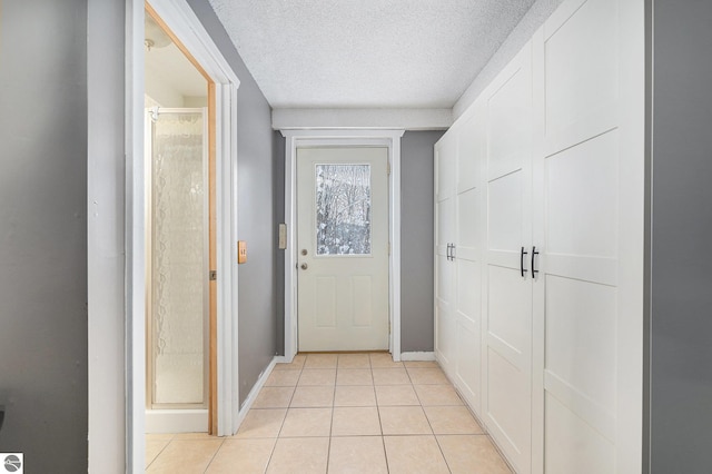 doorway to outside featuring a textured ceiling and light tile patterned floors