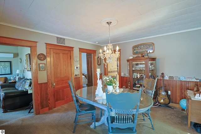 carpeted dining area featuring ornamental molding, wooden walls, a chandelier, and a wall unit AC