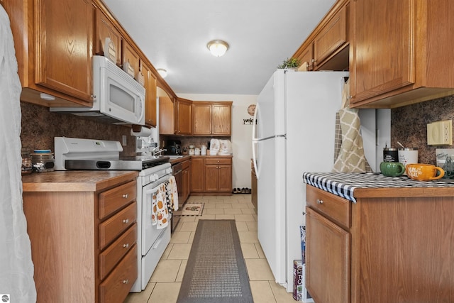 kitchen with tasteful backsplash, light tile patterned floors, and white appliances