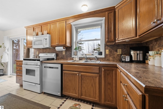 kitchen with white appliances, a wealth of natural light, sink, and light tile patterned floors