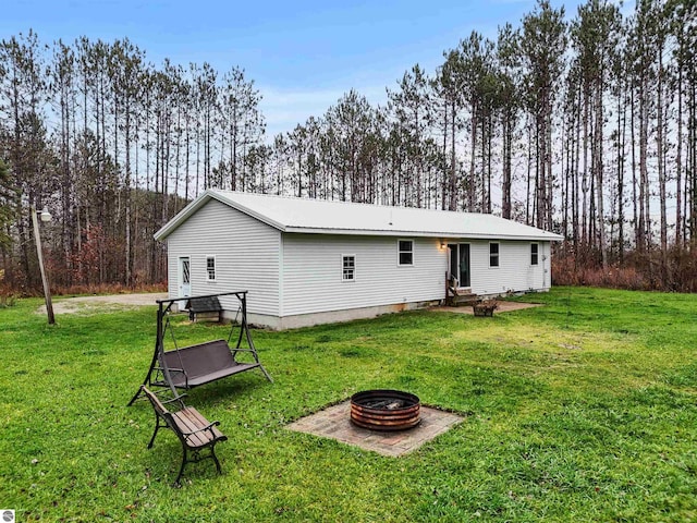 back of property with a yard and a fire pit