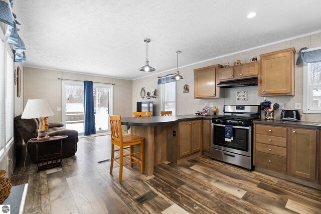 kitchen with pendant lighting, crown molding, stainless steel gas range, and a kitchen breakfast bar