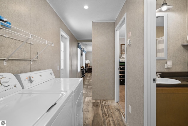 laundry room with hardwood / wood-style flooring, ornamental molding, washer and clothes dryer, and sink