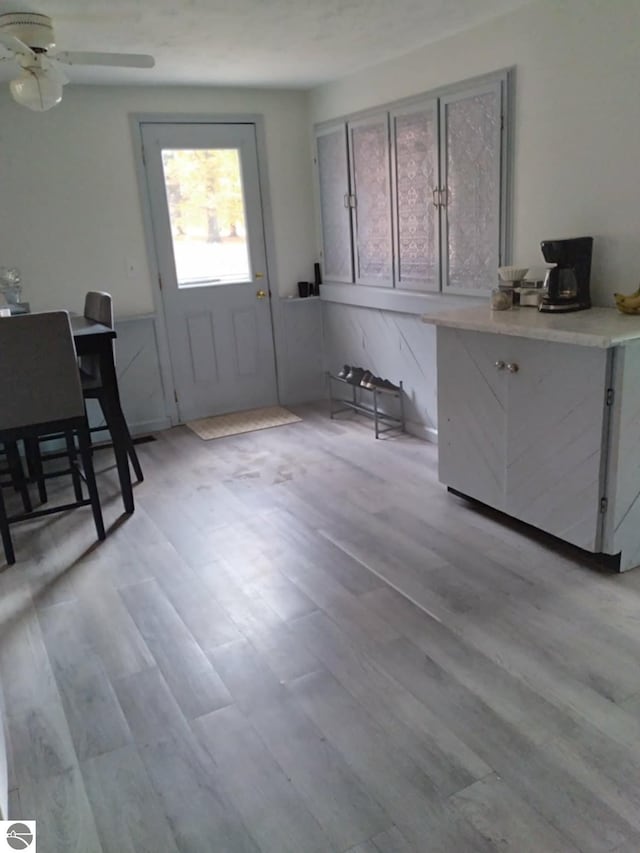 unfurnished dining area with ceiling fan and light wood-type flooring