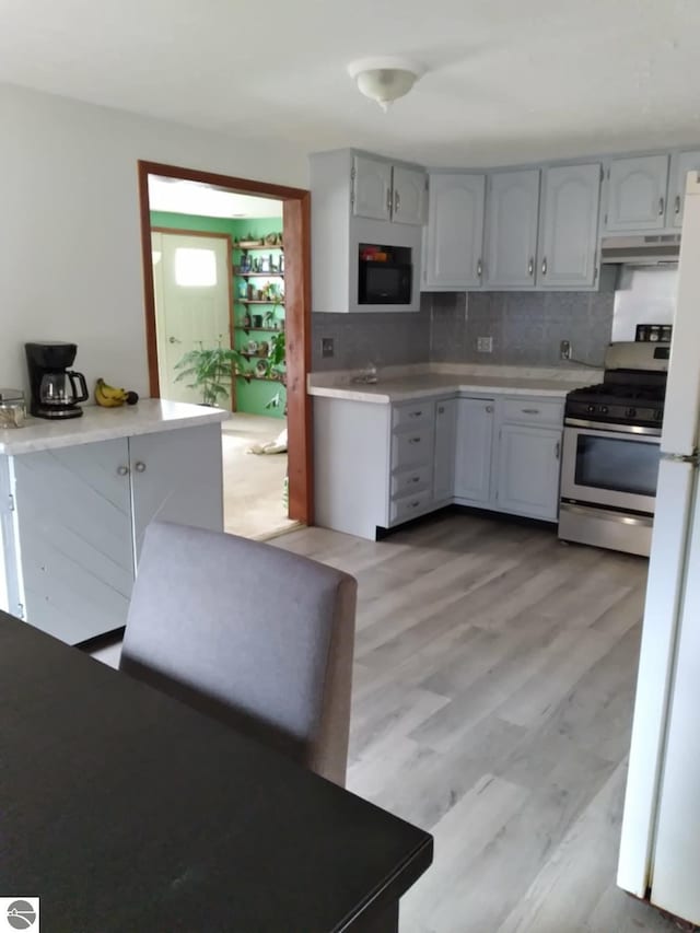 kitchen featuring tasteful backsplash, light wood-type flooring, and stainless steel gas range oven