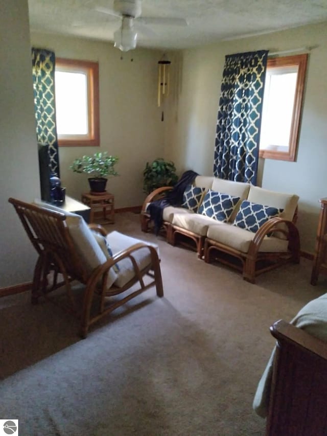 living room featuring ceiling fan, carpet flooring, and a wealth of natural light