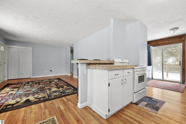 kitchen featuring white cabinetry, white gas stove, a textured ceiling, and light wood-type flooring