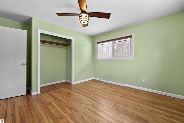 unfurnished bedroom with baseboard heating, ceiling fan, light hardwood / wood-style floors, and a closet