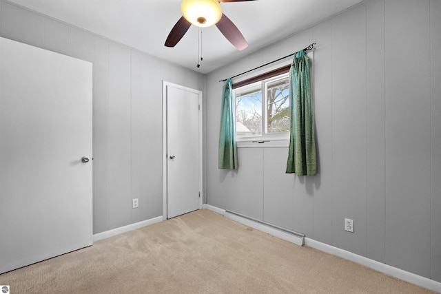 carpeted empty room featuring a baseboard heating unit and ceiling fan