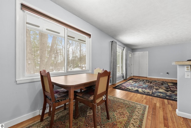 dining space with wood-type flooring and a textured ceiling