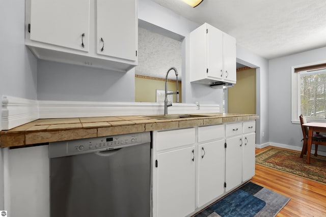 kitchen with sink, light hardwood / wood-style flooring, stainless steel dishwasher, and white cabinets