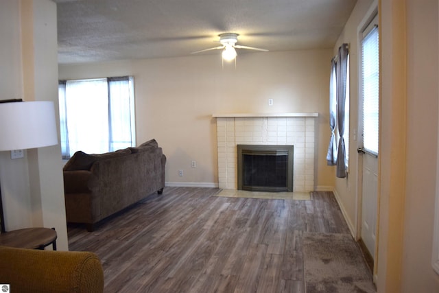 living room with a wealth of natural light, dark wood-type flooring, and a tile fireplace