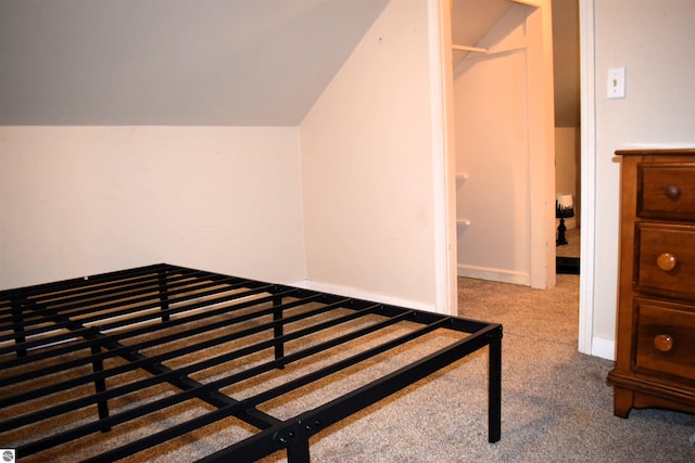 carpeted bedroom featuring vaulted ceiling and a closet