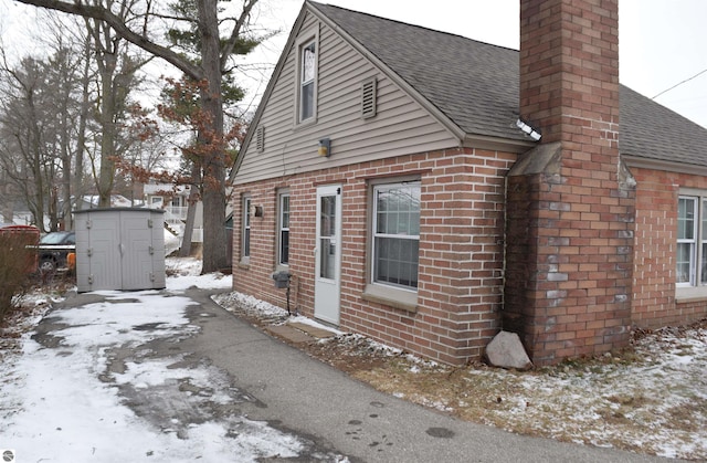 view of snow covered exterior featuring a storage shed