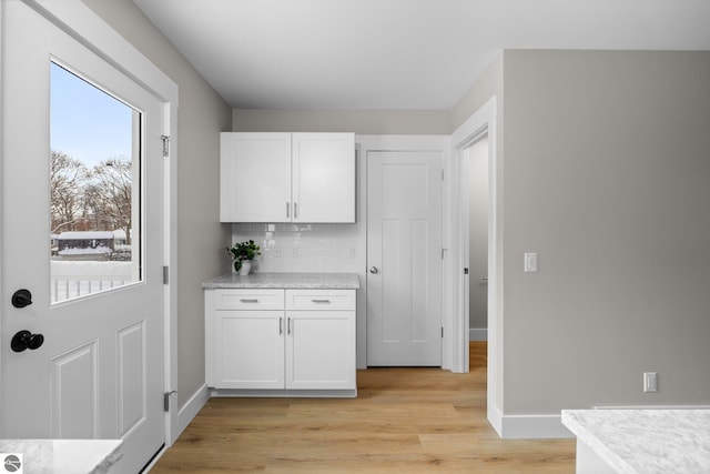 kitchen with white cabinetry, decorative backsplash, and light hardwood / wood-style flooring