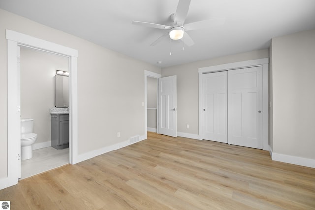 unfurnished bedroom with a closet, ceiling fan, light hardwood / wood-style floors, and ensuite bath