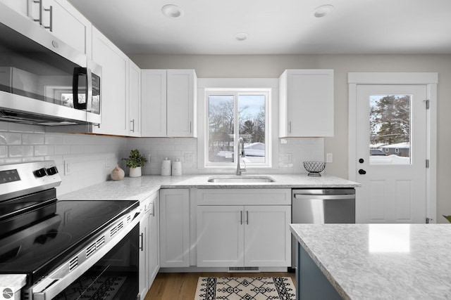 kitchen with stainless steel appliances, sink, white cabinets, and decorative backsplash