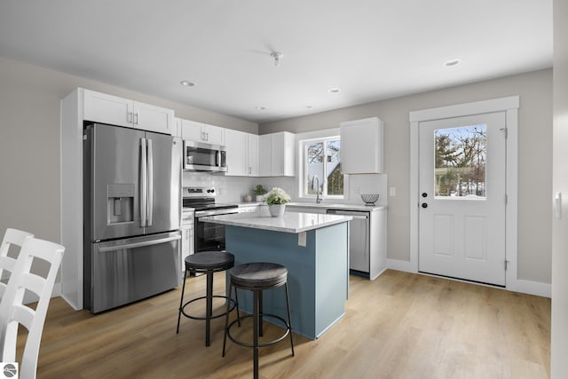 kitchen with white cabinetry, a center island, appliances with stainless steel finishes, and a breakfast bar