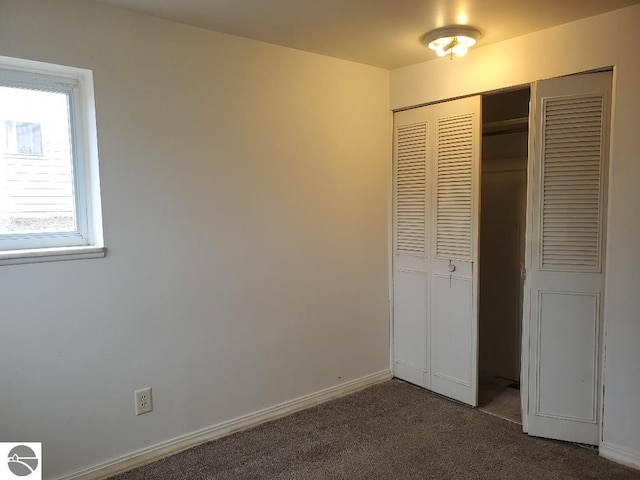 unfurnished bedroom featuring dark carpet and a closet